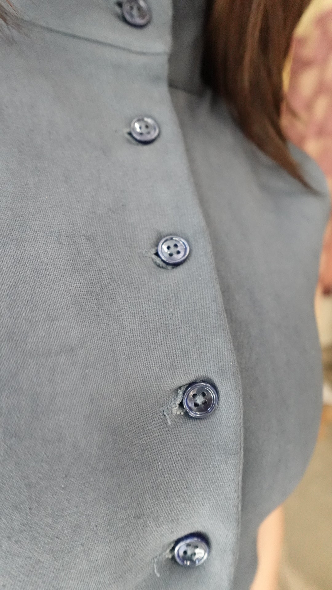 Close-up of a gray garment with buttons on a blurred background