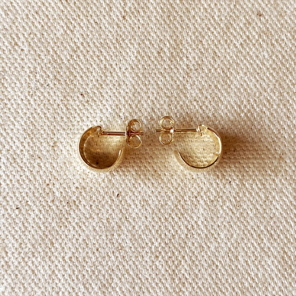 Gold hoop earrings on a beige fabric background