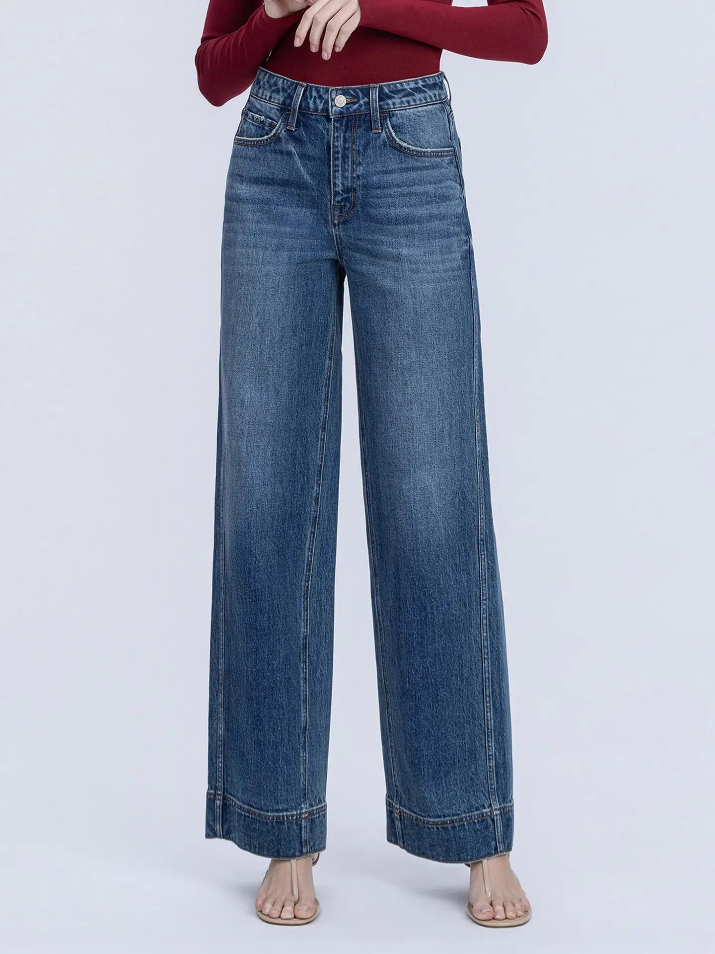 Blue jeans worn by a person on a light purple background