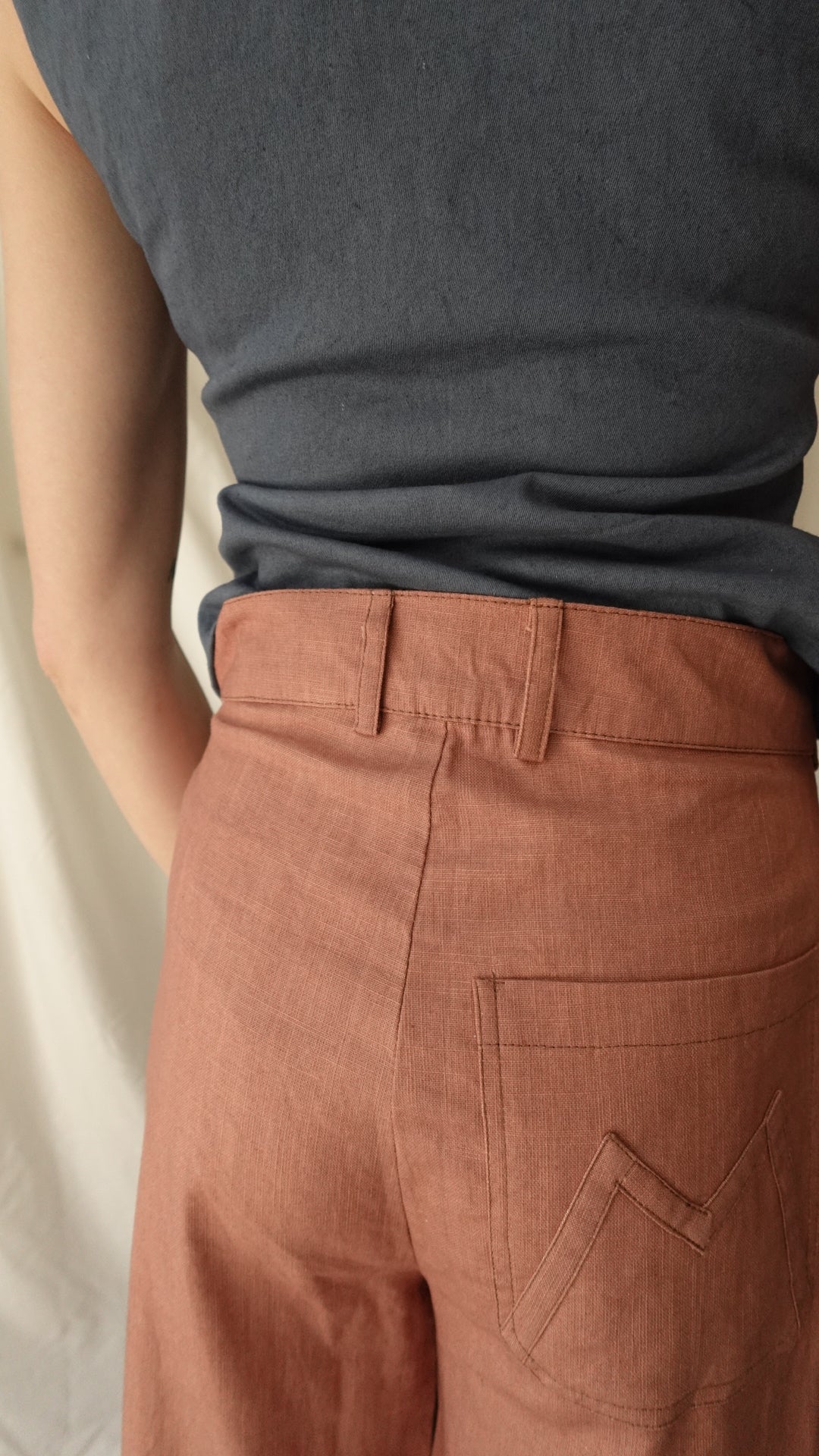 Close-up of a person wearing a gray shirt and brown pants.