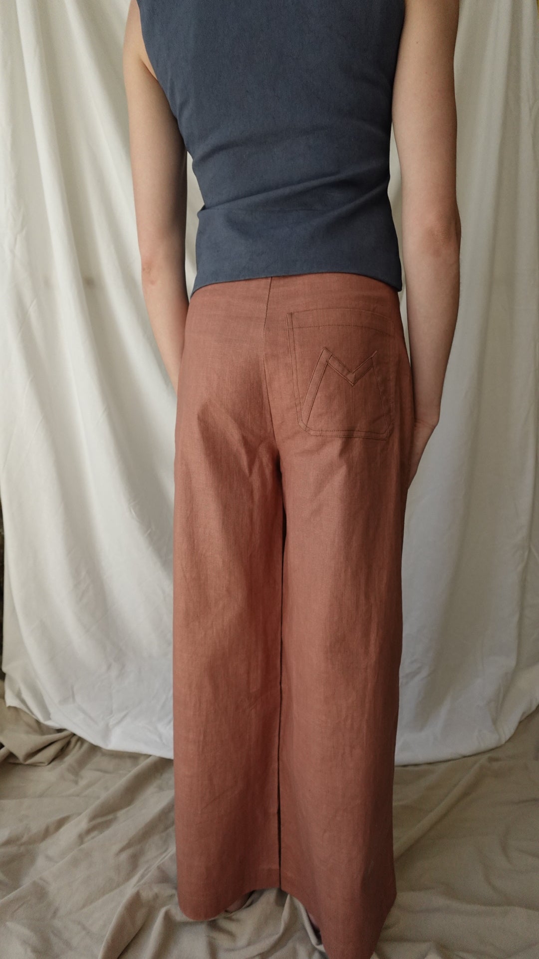 Person wearing brown pants and a dark shirt on a beige bed.