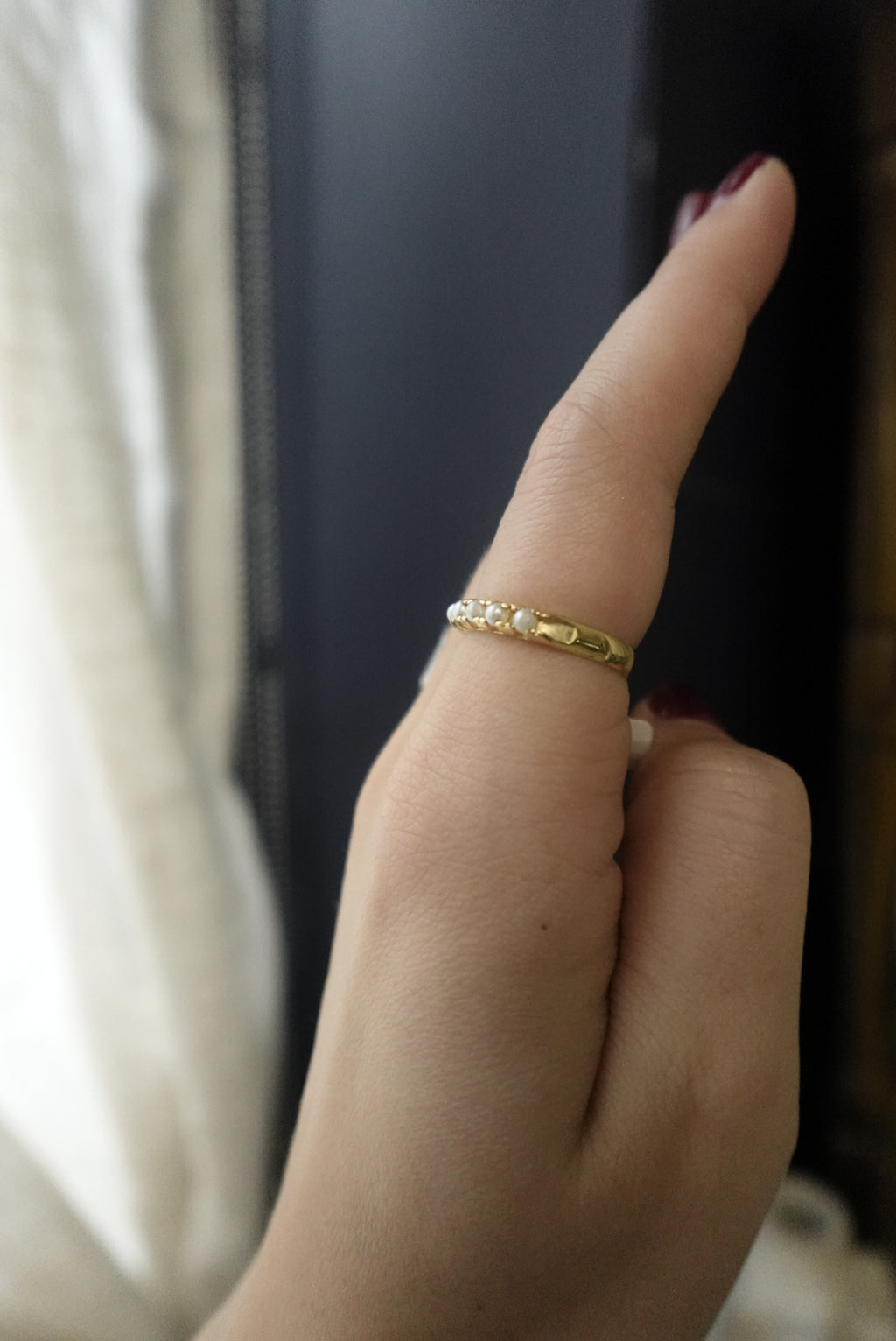 Close-up of a hand wearing a gold ring with a blurred background