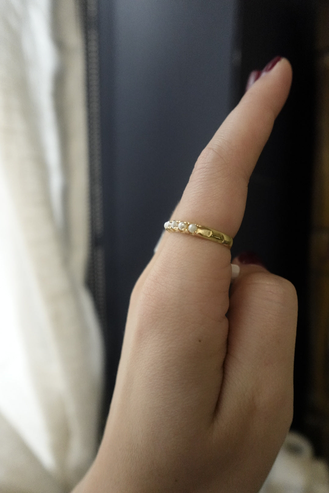 Close-up of a hand wearing a gold ring with a blurred background